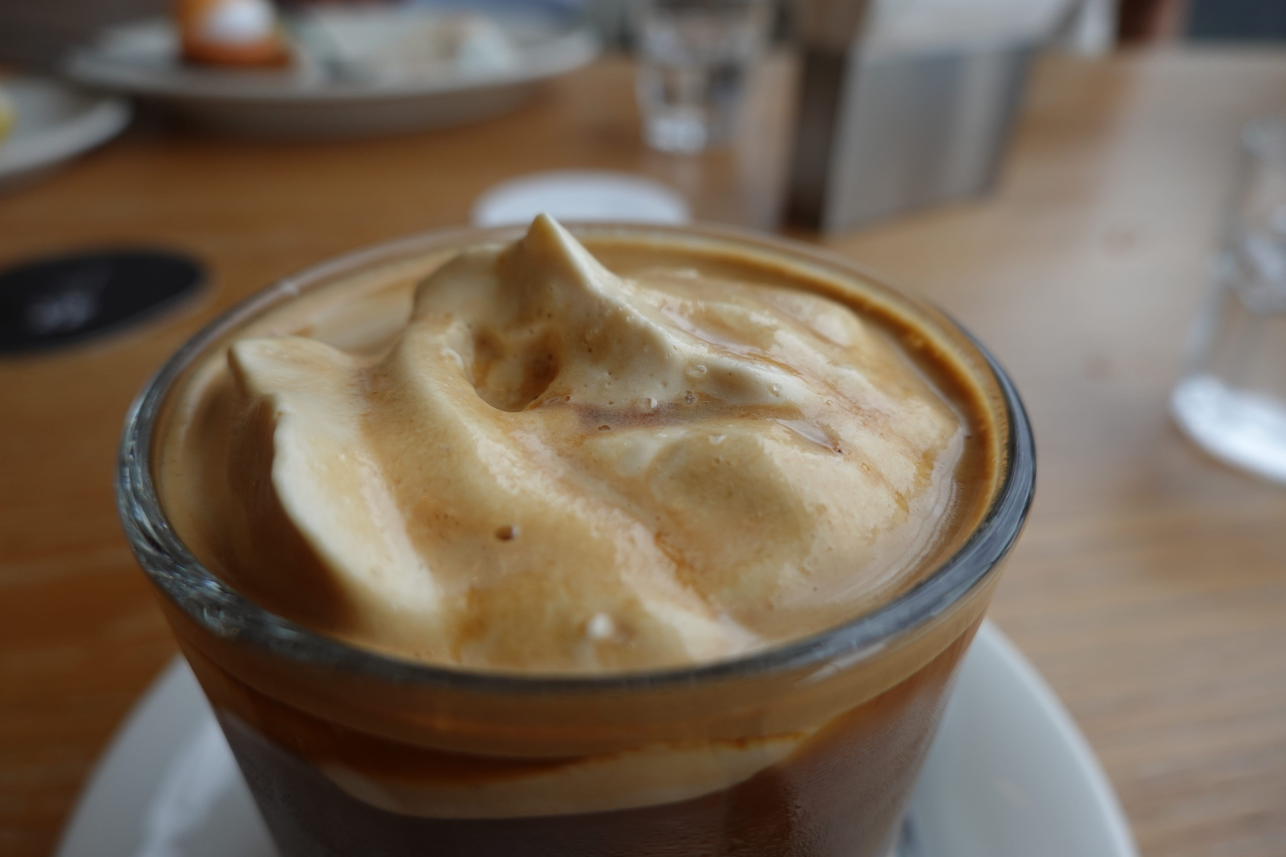 Close-up of iced espresso topped with thick whipped cream, showing creamy swirls on the surface.