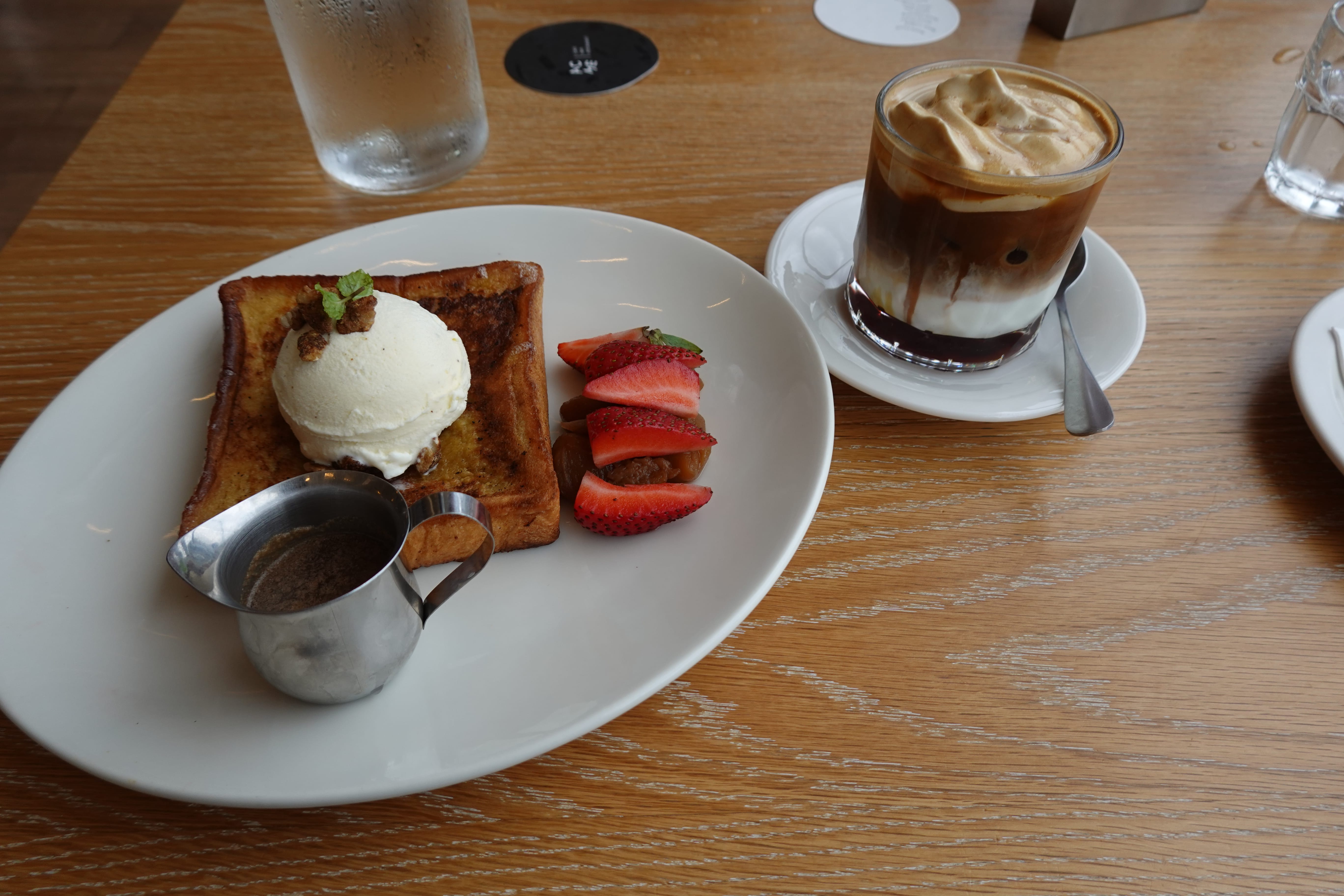 French toast with vanilla ice cream and strawberries on a plate, served beside an iced espresso float.