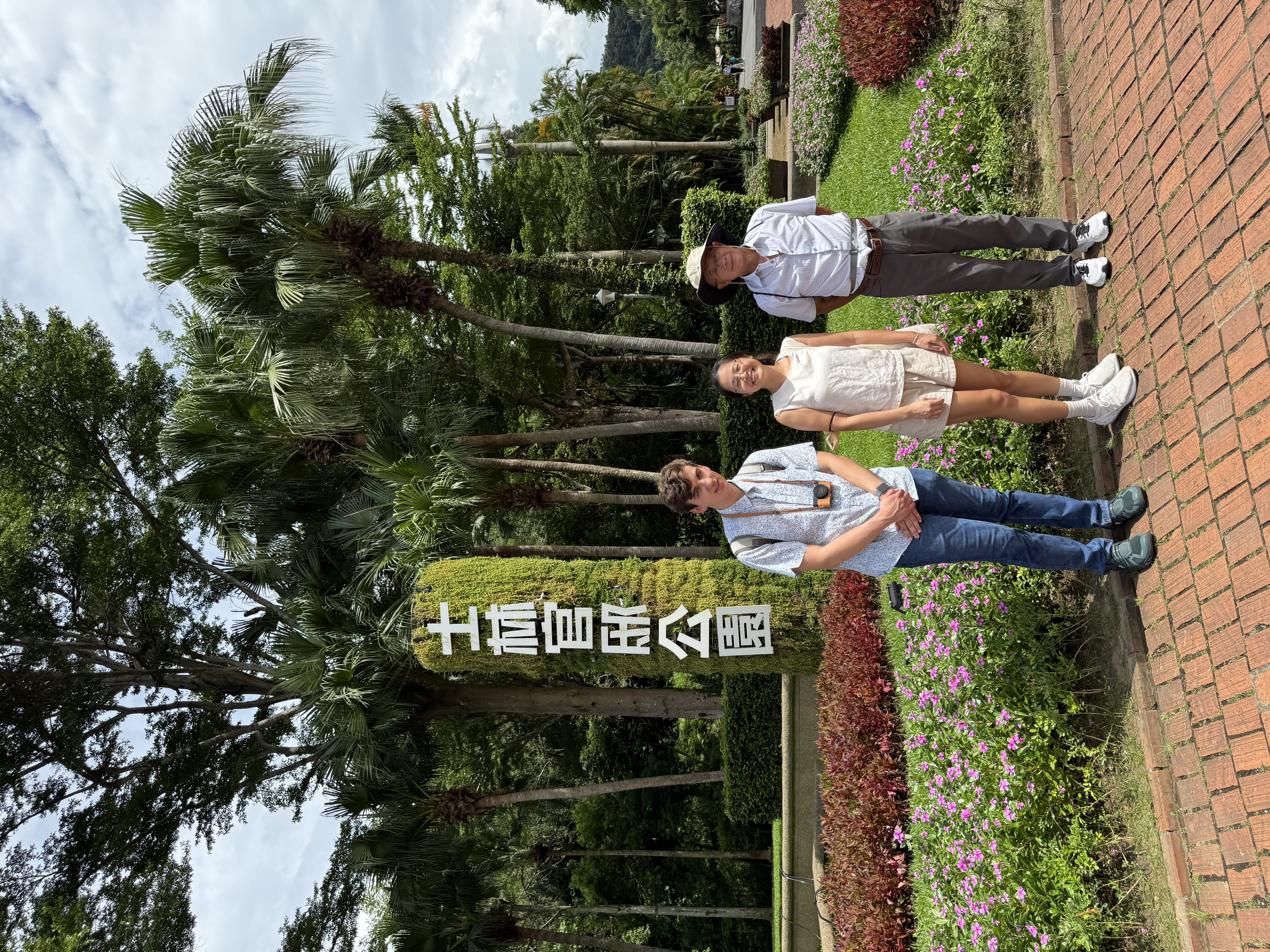 Three people posing by a vertical sign reading ‘士林官邸公園’ at Shilin Official Residence Park.