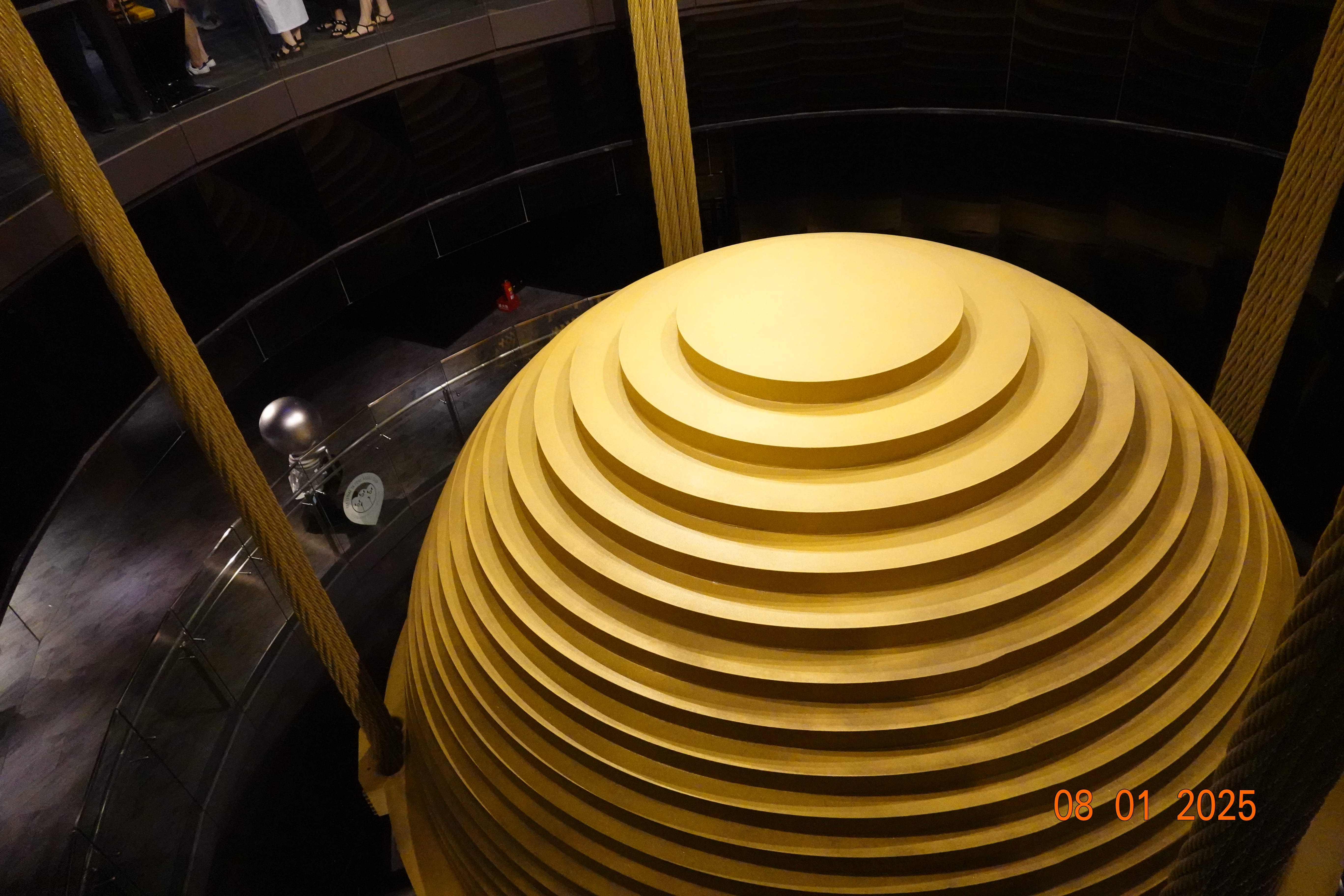 Close-up of Taipei 101’s giant gold tuned-mass damper showing concentric stepped rings and suspension cables.