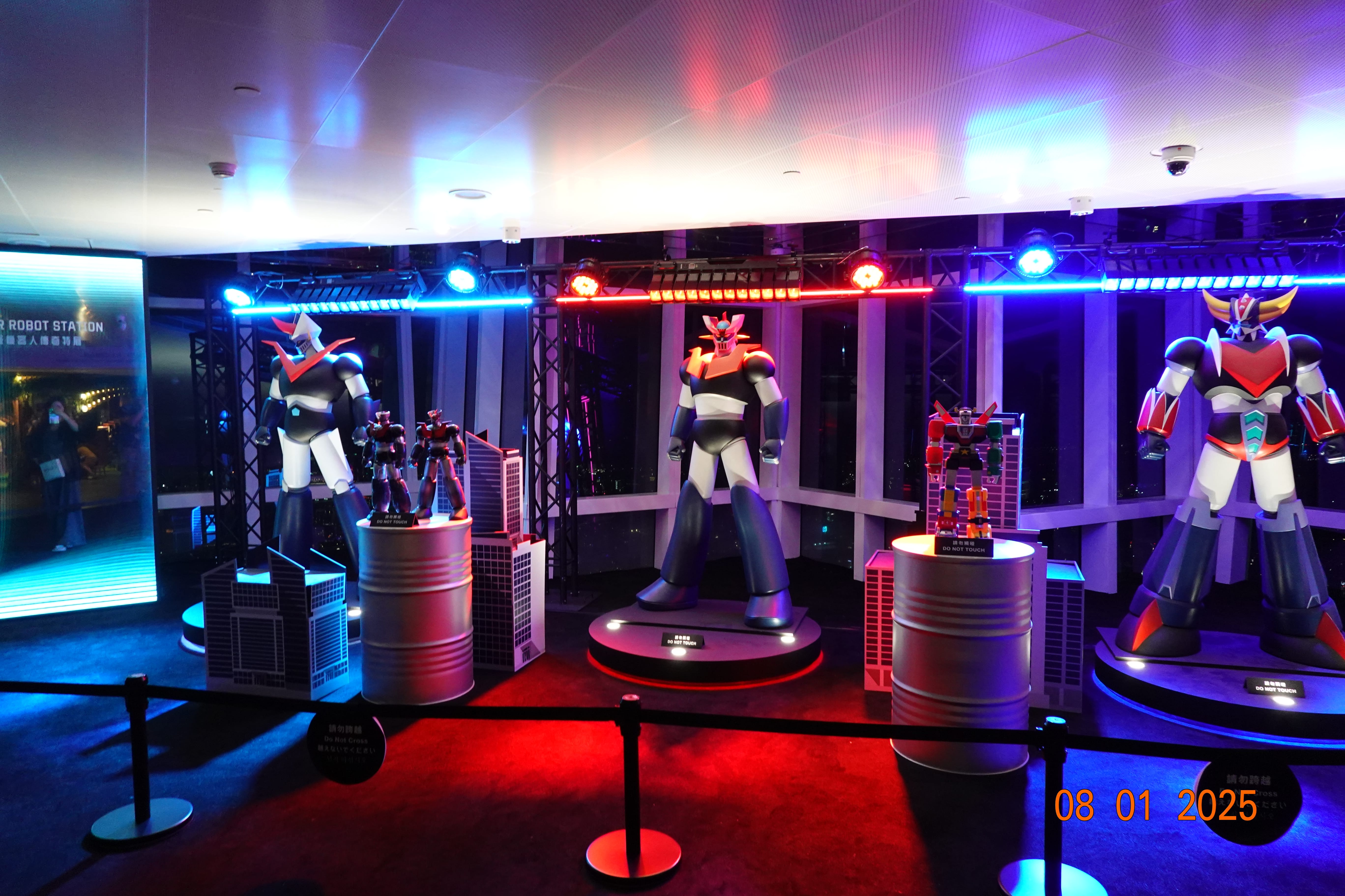 Exhibit of giant robot figures under red and blue lighting on the observation floor, with smaller models on pedestals.